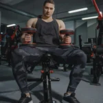 A Bodybuilder Holding Dumbbells While Sitting